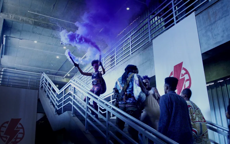 People escape up a stairway amid purple smoke and sparks in Kwese’s The Great Escape