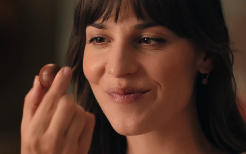 A woman smiles as she unwraps a Lindor chocolate in Lindt’s Job Well Done