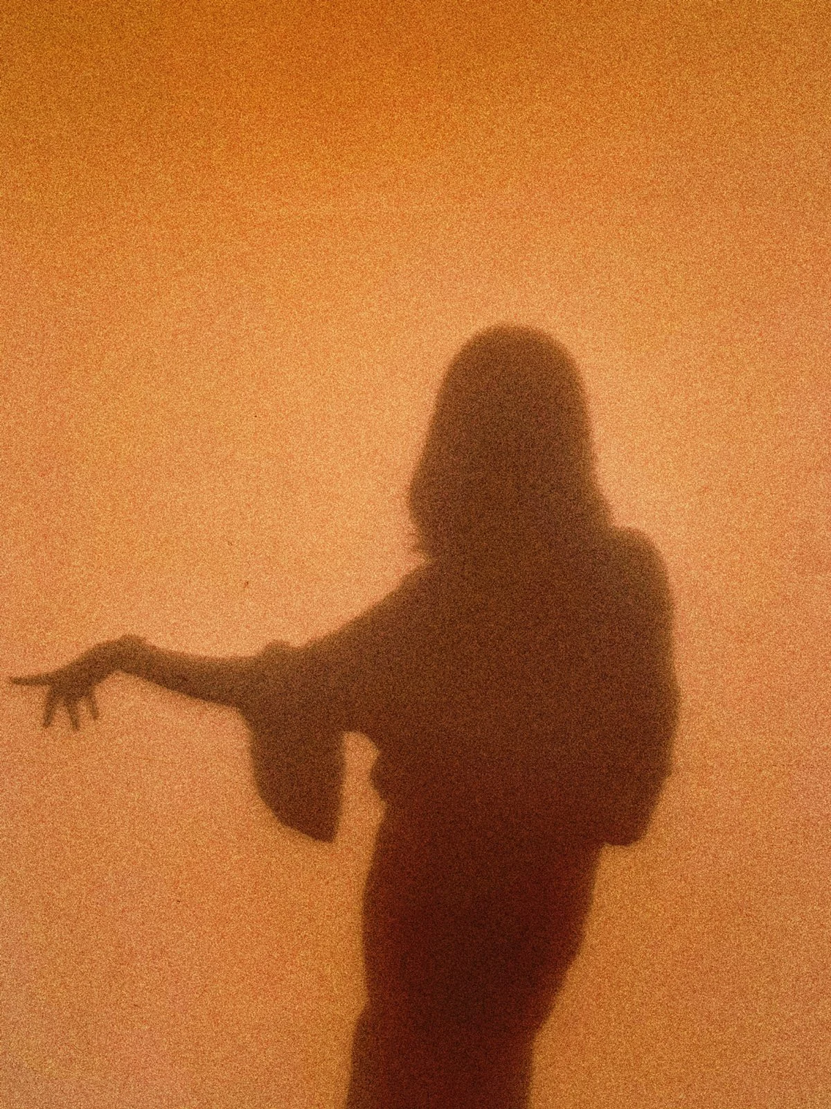 A woman’s shadow, her arm extended in an expressive gesture