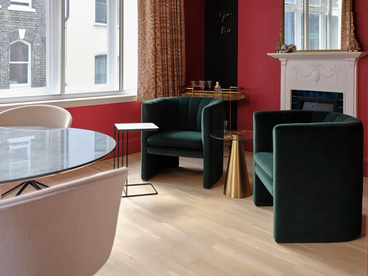 Green armchairs beside the fireplace in ELEANOR’s London office