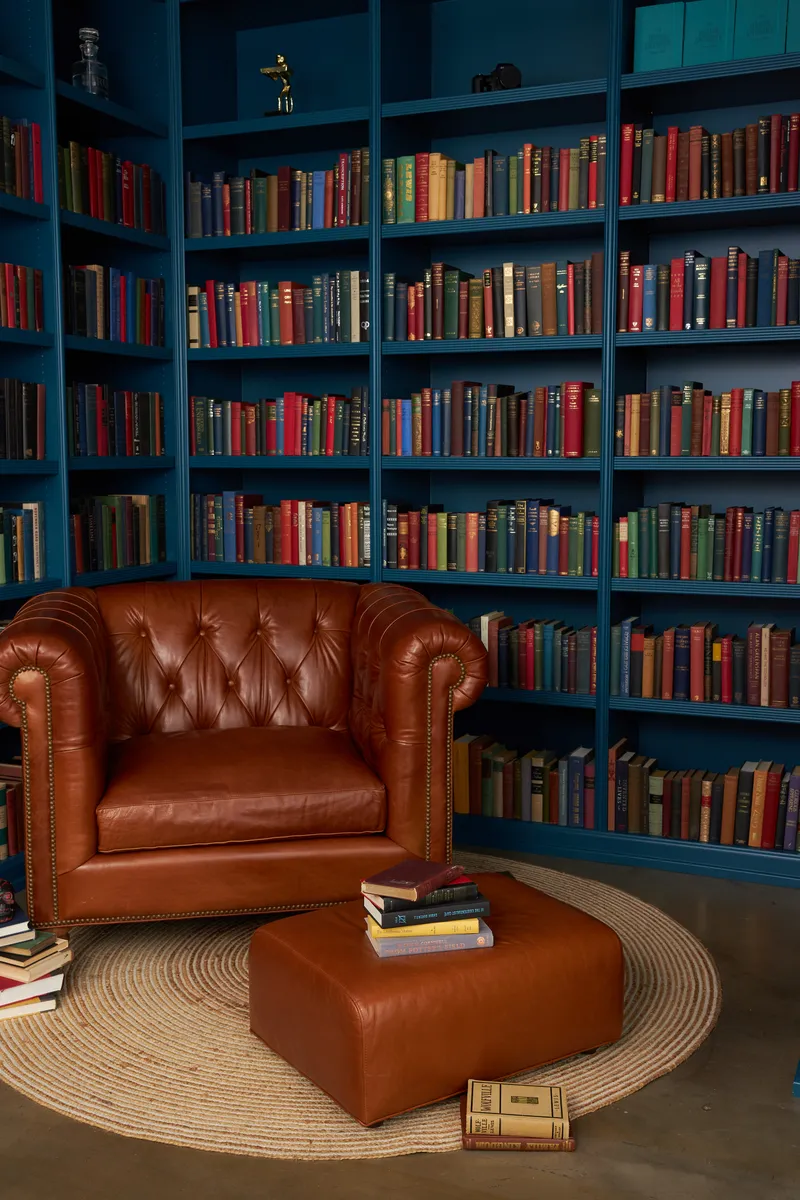Teal bookshelves and leather reading chair in ELEANOR’s Santa Monica library