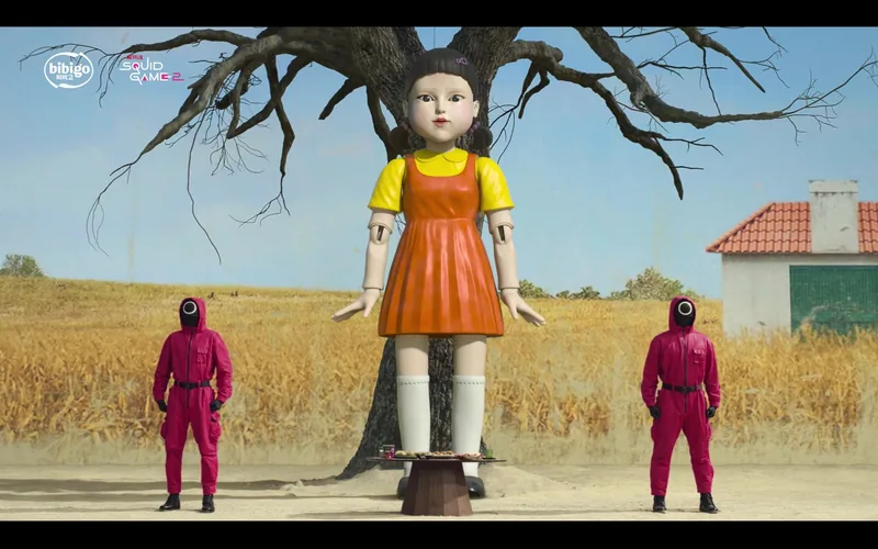 A giant doll stands between two pink-clad guards.