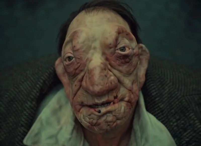 A stylised character with an oversized face looks towards the camera.