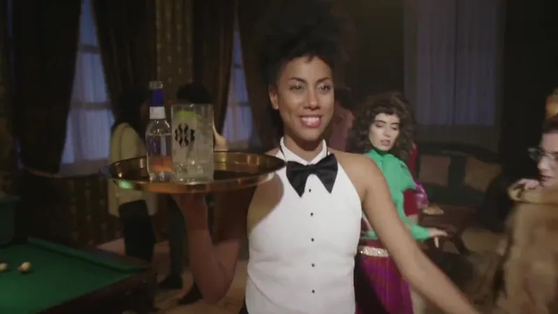 A smiling server carries a tray through a bar.
