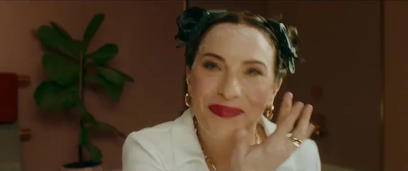 A woman with pinned-up dark hair gestures beside her face.