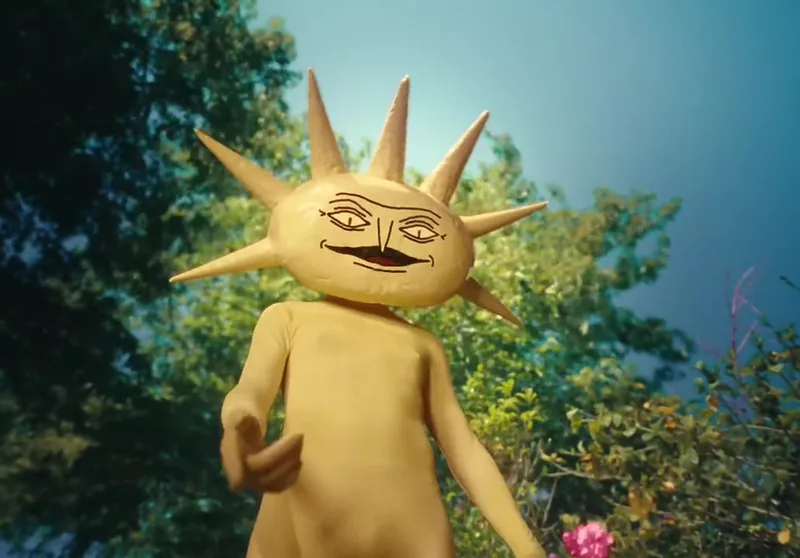 A yellow sun character gestures in a garden.