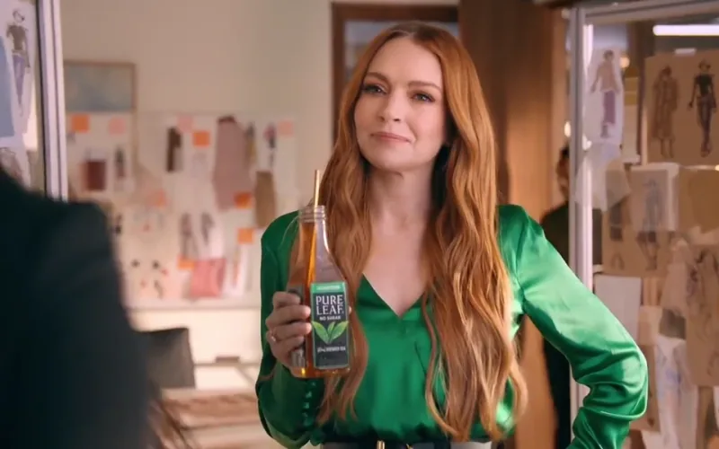 Lindsay Lohan holds a Pure Leaf bottle with one hand on her hip during an office tea break.