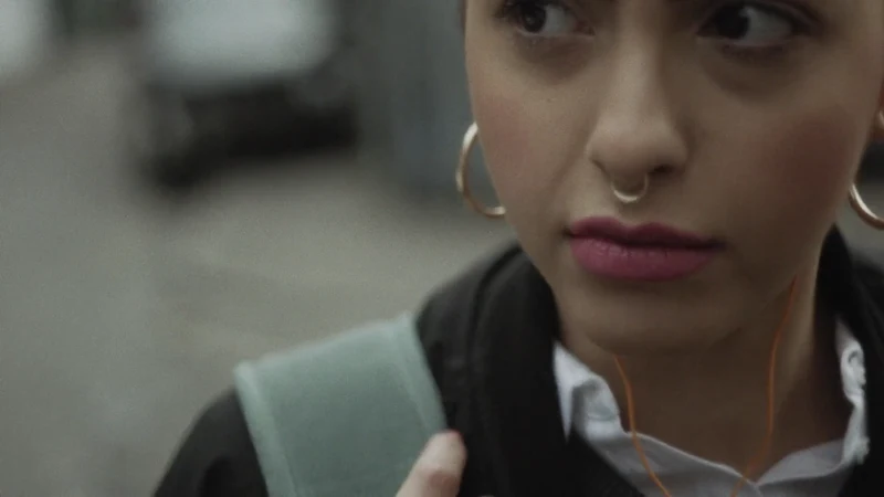 A woman with earphones looks to the side in Georgia Oakley’s Tell MAMA film