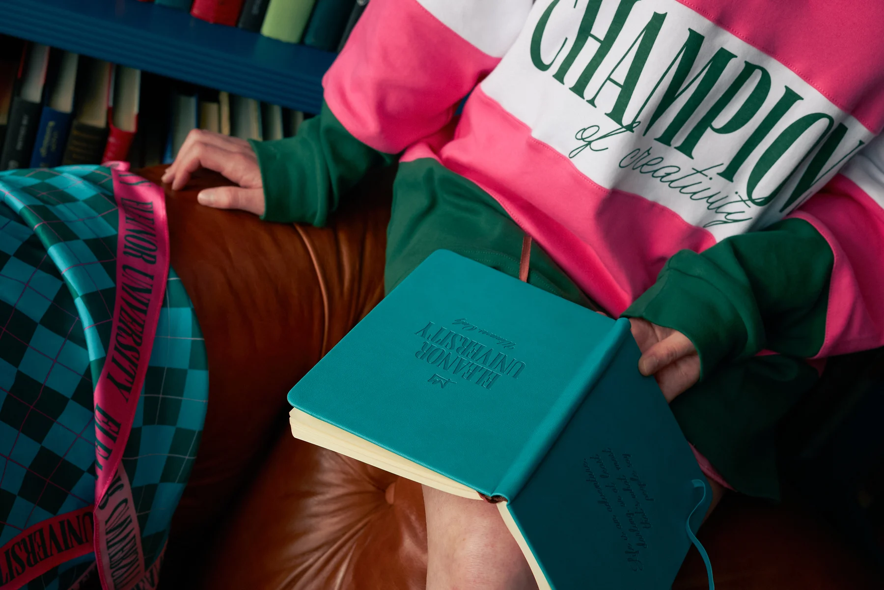 Neck-down detail of the pink, white and forest-green Champions of Creativity rugby shirt, with its striped sleeves and front lettering