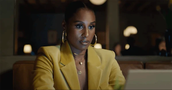Issa Rae in a yellow jacket at a restaurant table in American Express’s When Inspiration Hits